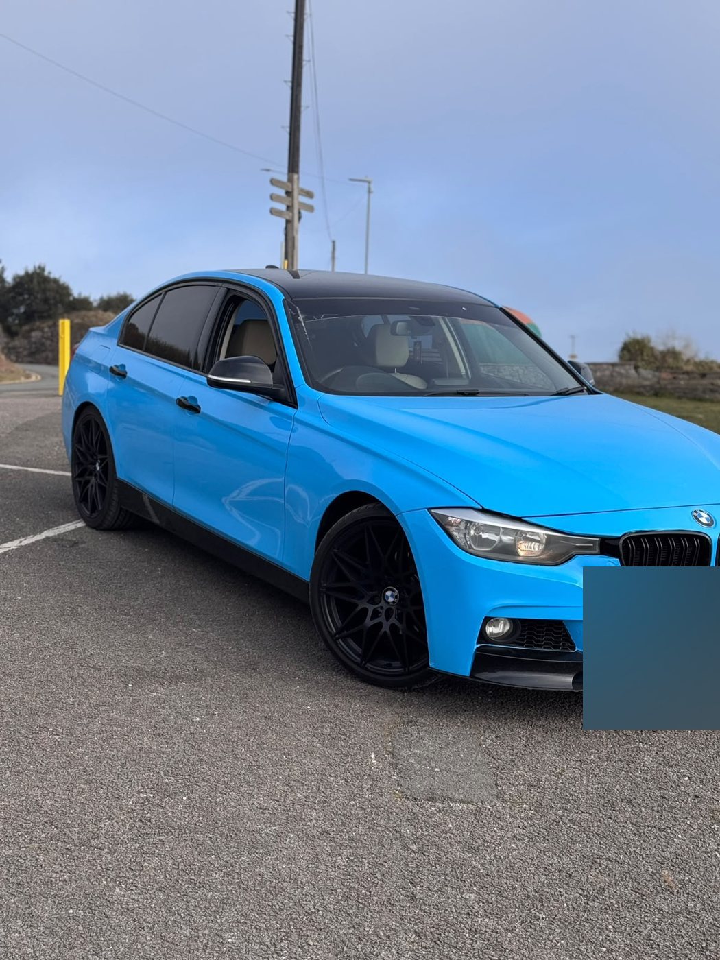 Front detail of the gloss blue BMW 3 Series showing the wrapped bumper edge