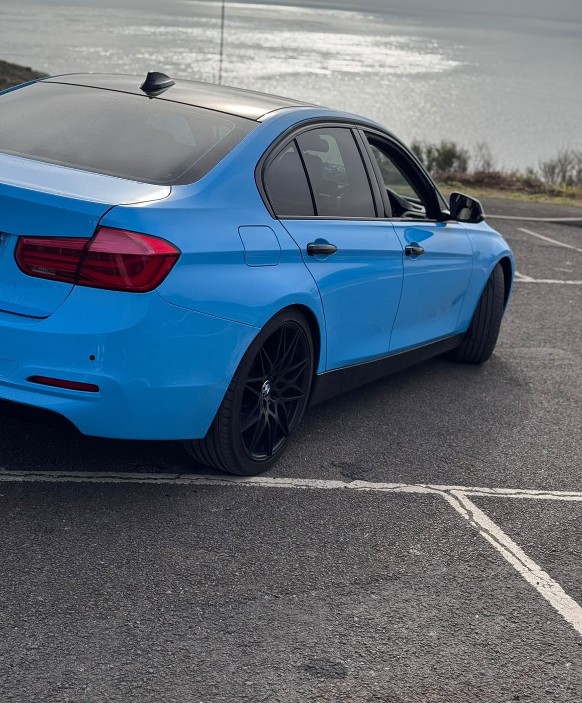 Rear detail of the gloss blue BMW 3 Series showing wrapped panel edges and tinted glass