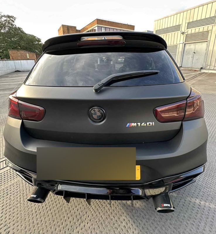 BMW M140i wrapped in matte dark grey, rear view with quad exhaust